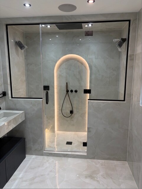 Modern glass shower enclosure with arch lighting